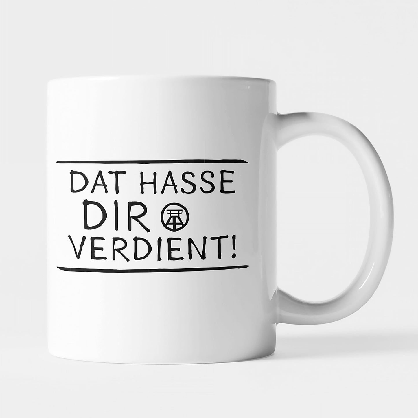 Weiße Keramiktasse mit schwarzem Ruhrpott-Spruch 'Dat hasse dir verdient!', beidseitig bedruckt.