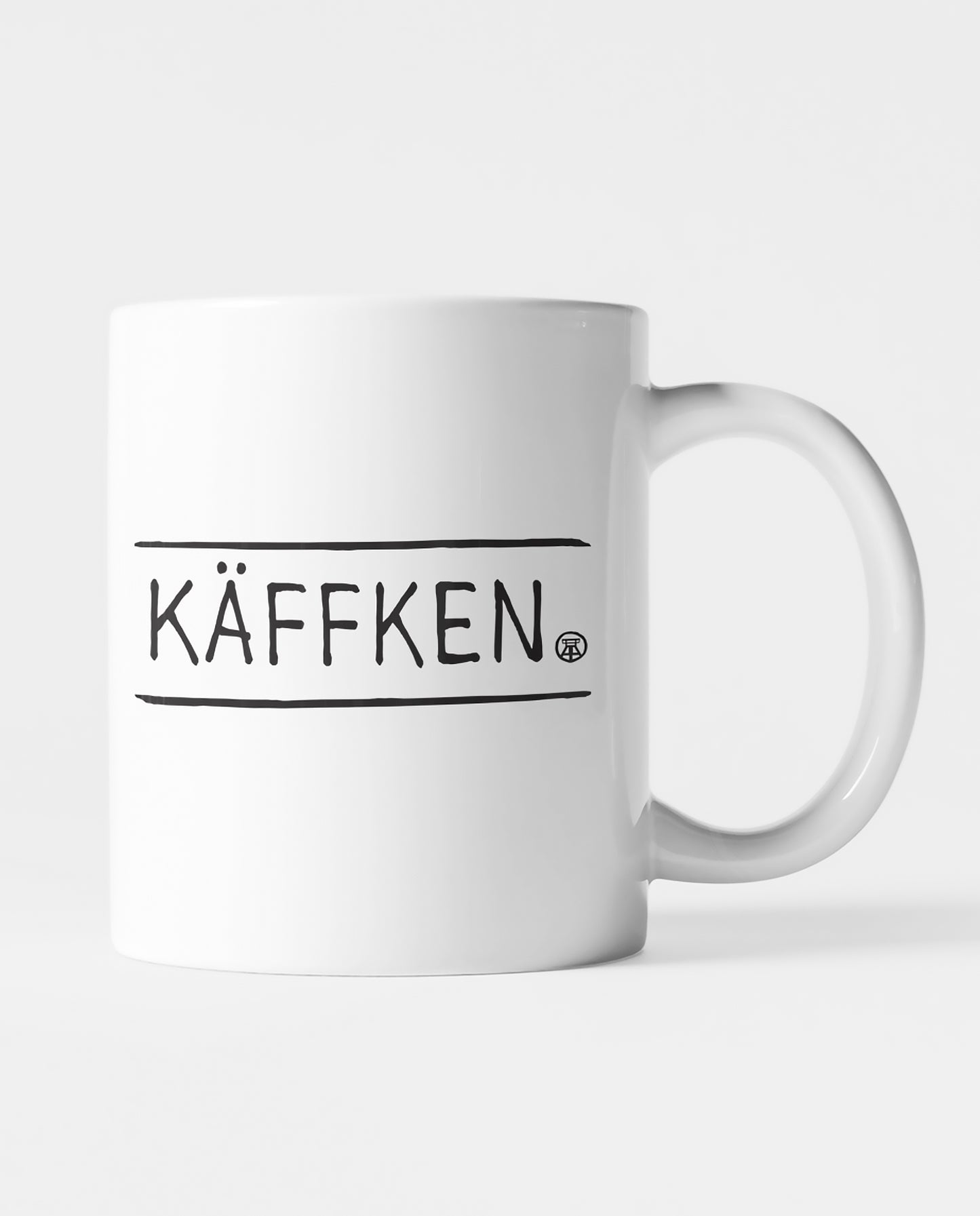 Weiße Keramiktasse mit schwarzem 'KÄFFKEN'-Schriftzug, perfekt für Kaffee- und Teeliebhaber:innen.