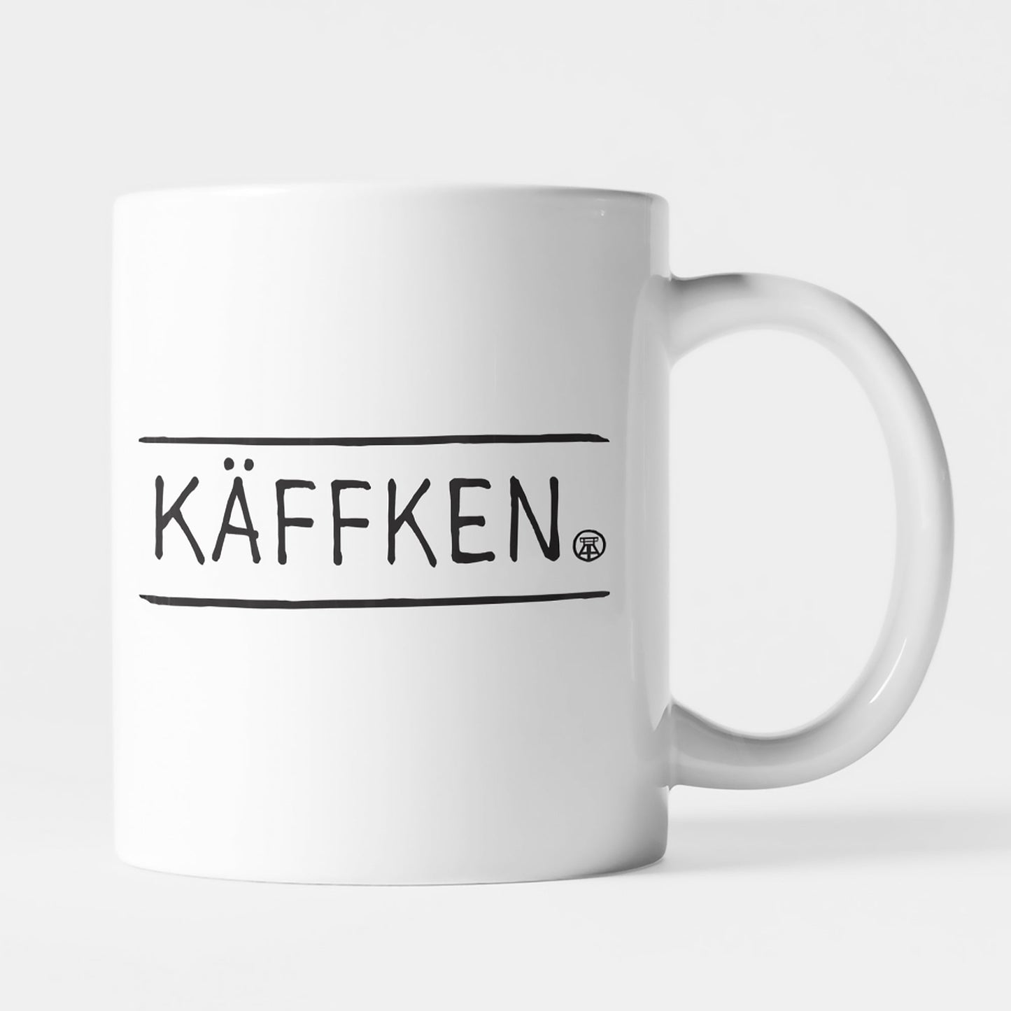 Weiße Keramiktasse mit schwarzem 'KÄFFKEN'-Schriftzug, perfekt für Kaffee- und Teeliebhaber:innen.