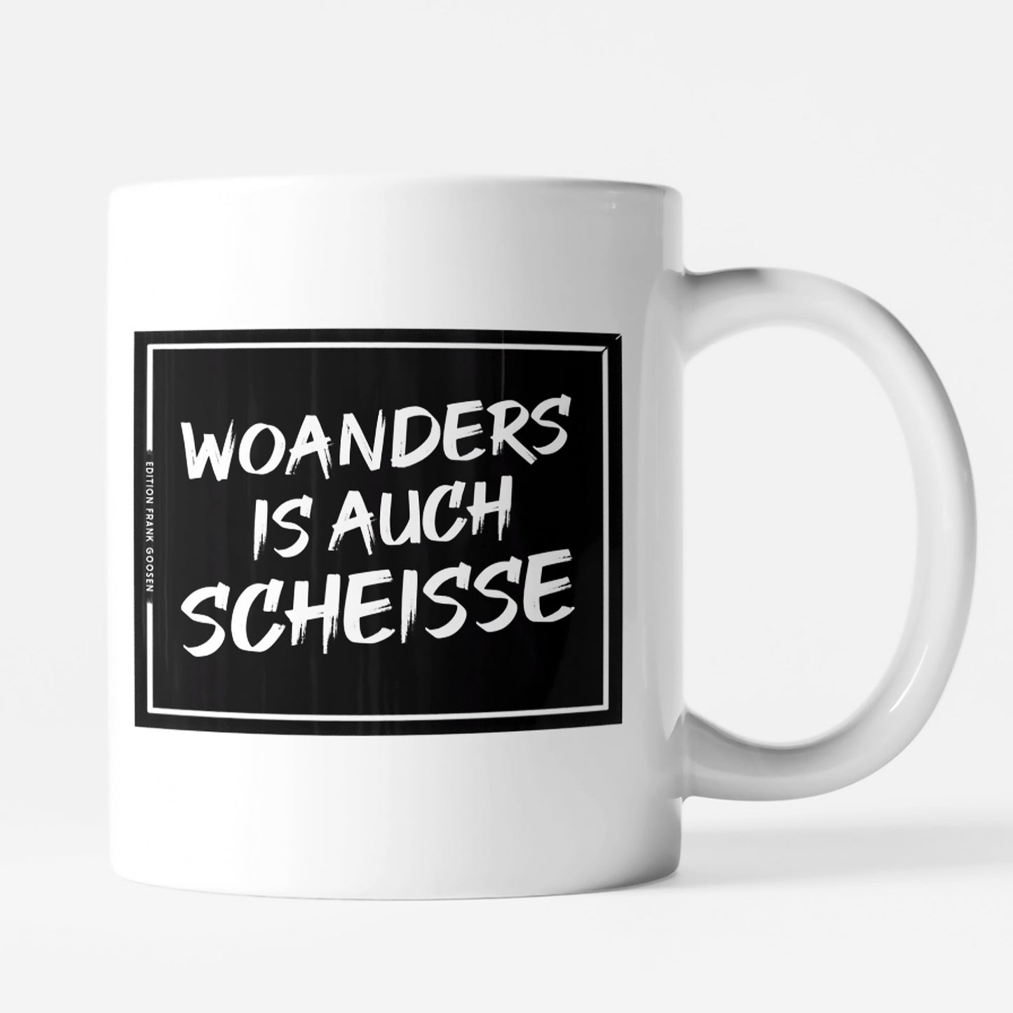 Weiße Keramiktasse mit schwarzem Print und dem Ruhrpott-Spruch 'Woanders is auch scheiße' von Frank Goosen.
