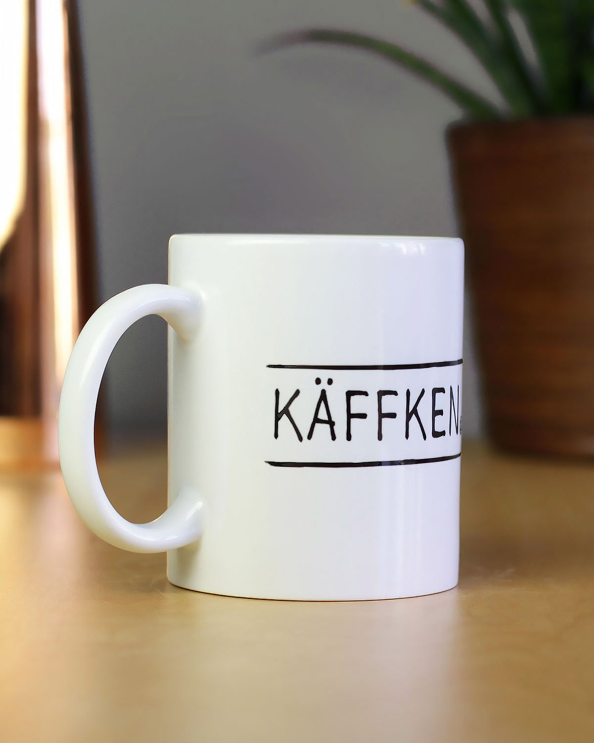 Kaffeetasse mit schlichten, schwarzen Buchstaben 'KÄFFKEN', passend für Fans des Ruhrgebiets.