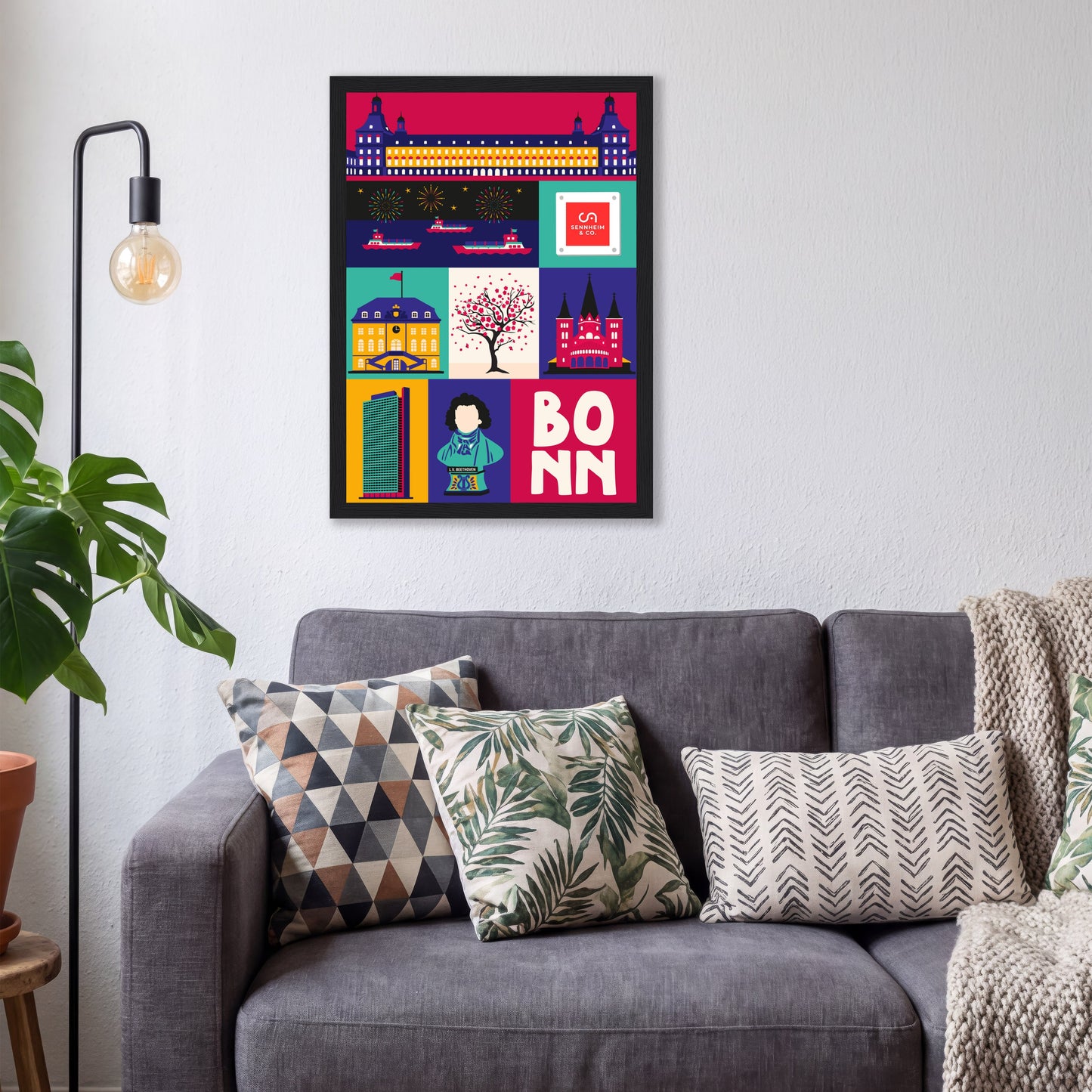 Gerahmtes Pop-Art Poster der Stadt Bonn mit integriertem Firmenlogo über einem grauen Sofa.