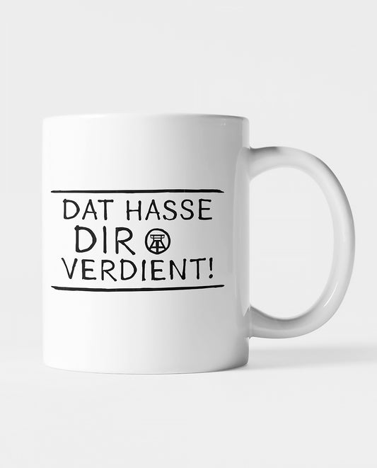 Weiße Keramiktasse mit schwarzem Ruhrpott-Spruch 'Dat hasse dir verdient!', beidseitig bedruckt.