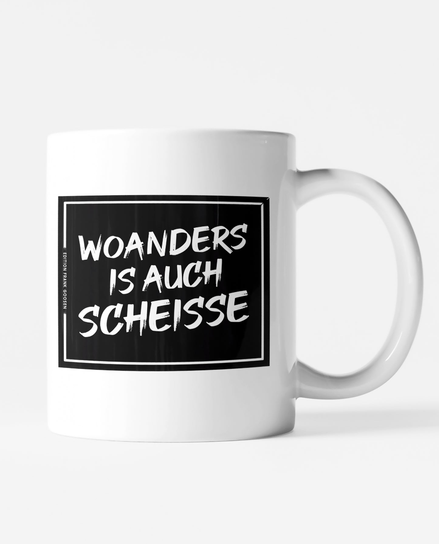 Weiße Keramiktasse mit schwarzem Print und dem Ruhrpott-Spruch 'Woanders is auch scheiße' von Frank Goosen.